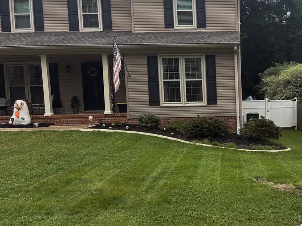 A striped front lawn running up to a two-storey home, edged along the walk.