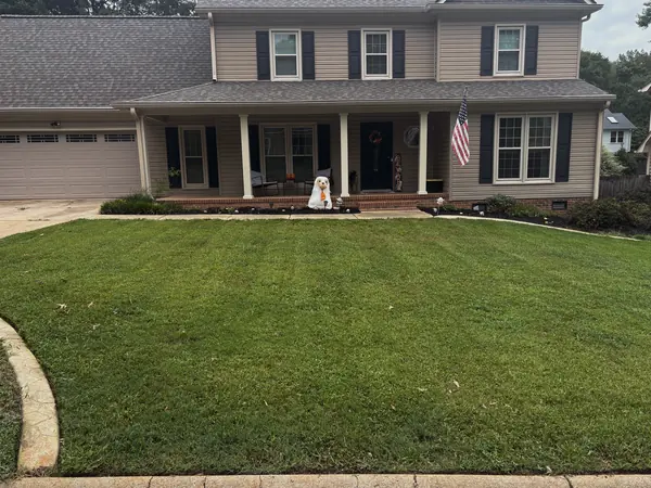 A wide front lawn mown in even stripes across the full frontage of a house.